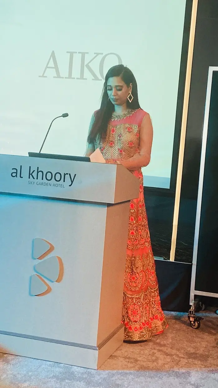 Pooja Sudha hosting at an AIKO corporate event podium