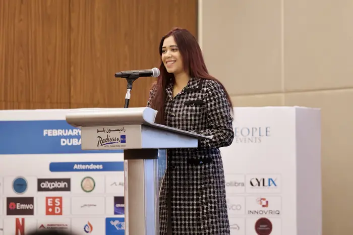 Pooja Sudha smiling on stage at a corporate conference