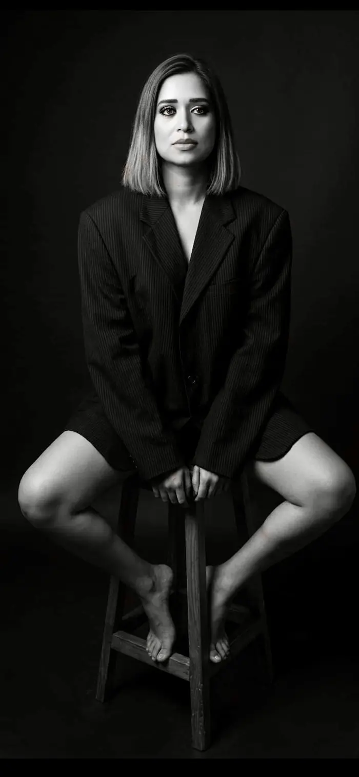 Pooja Sudha black and white editorial portrait seated on a stool