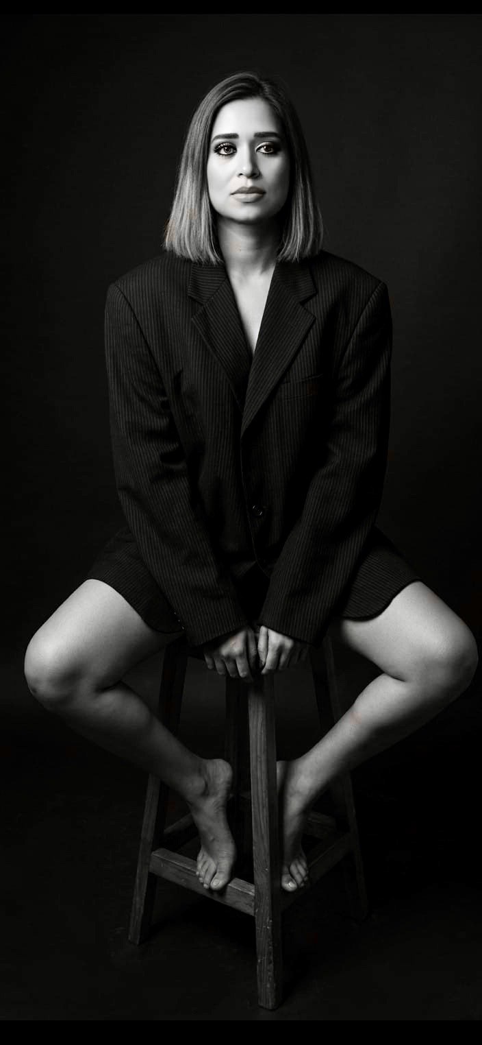 Pooja Sudha black and white editorial portrait seated on a stool